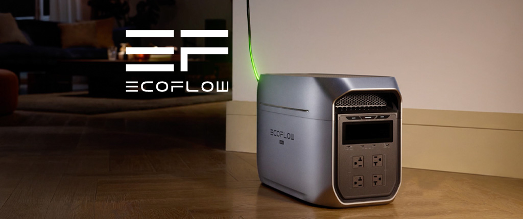 Power station EcoFlow Delta Pro συνδεδεμένο σε εσωτερικό χώρο σπιτιού, με φωτιζόμενο πράσινο καλώδιο φόρτισης. Τοποθετημένο σε ξύλινο πάτωμα δίπλα σε τοίχο, με το λογότυπο EcoFlow να προβάλλεται δίπλα.